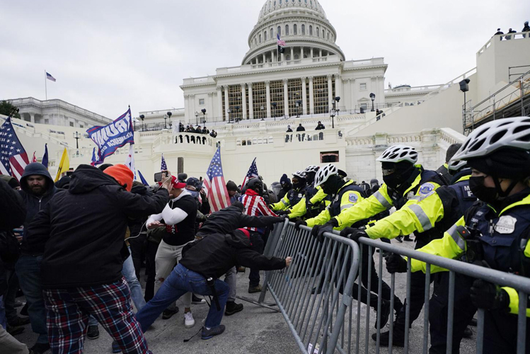 A crowd knocking down a fence at the capitol